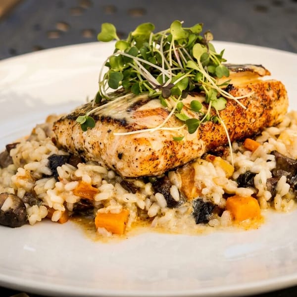 Grilled fish fillet on creamy risotto with mushrooms, butternut squash, and microgreens.